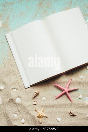 Vorlage für den Sommer. Reiseplanung. Notizblock, kleine Muscheln, Seesterne auf Sand. Platzieren Sie Text auf leeren weißen Notizblock-Seiten. Stockfoto