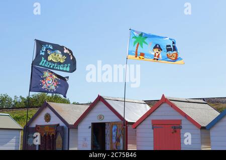 Flaggen auf den Strandhütten in der Küstenstadt Paignton, Devon Stockfoto