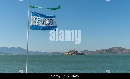 San Francisco, Kalifornien, USA - August 2019: Pier 39 Flagge von Fisherman's Wharf mit Alcatraz Insel im Hintergrund Stockfoto