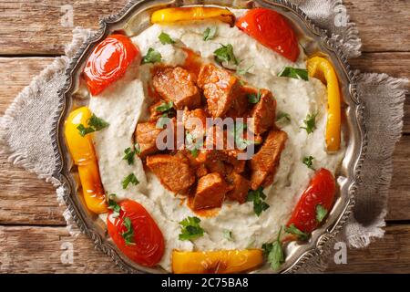 Ali Nazik Kebab ist zartes, saftiges Lamm, das auf einem Bett aus heiß gerösteter Aubergine serviert wird, das mit schlichtem Joghurt in der Nähe auf dem Teller auf dem Tisch gepeitscht wird. hori Stockfoto