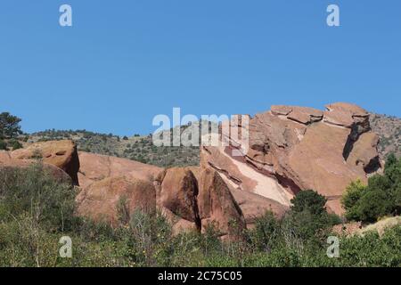 Große gescherte Felsformationen zwischen immergrünen, Bäumen und Sträuchern auf dem Trading Post Trail im Red Rocks State Park, Colorado, USA Stockfoto