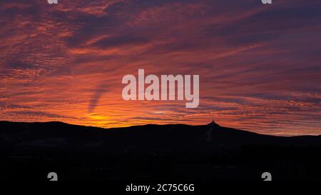 Silhouette des Jested Berges bei Sonnenuntergang mit einem wunderschönen beleuchteten Abendhimmel, Liberec, Tschechische Republik. Stockfoto