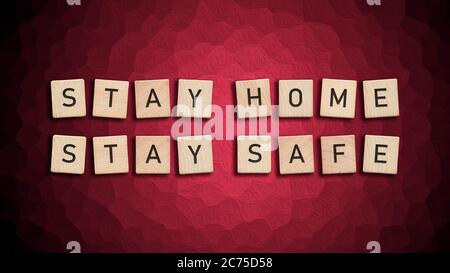 Stay Home Stay Safe mit Holzfliesen auf rotem Hintergrund geschrieben. Quarantänemaßnahmen für Covid-19 erfordern Isolation und Arbeit von zu Hause aus. Virus Pande Stockfoto