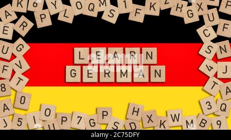 Lernen Sie Deutsch Wort geschrieben mit Holzfliesen über deutscher Flagge. Dieses Bild kann für ein Banner oder eine Postkarte verwendet werden. Stockfoto