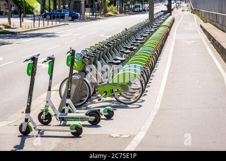 Eine Flotte von etwa sechzig Velib gemeinsam Fahrräder, zusammen mit drei Lime Elektro-Scooter, sind ordentlich an einer Anlegestelle in Paris, Frankreich aufgereiht. Stockfoto