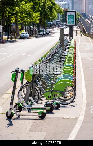 Eine Flotte von etwa sechzig Velib gemeinsam Fahrräder, zusammen mit drei Lime Elektro-Scooter, sind ordentlich an einer Anlegestelle in Paris, Frankreich aufgereiht. Stockfoto