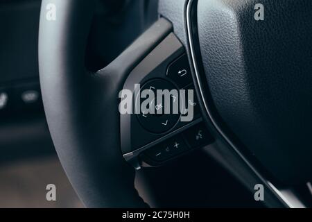 Nahaufnahme modernes schwarzes Lenkrad mit Multifunktionstasten integrierte Stereo-Bedienelemente drücken die für schnelle Steuerungstechnik im Auto. Stockfoto