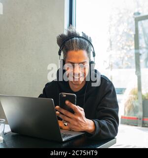 Der junge Mann ist mit seinem Laptop und Smartphone verbunden, der junge Student schafft neue ides und Projekt im Web, Lifestyle-Konzept von Blogger und inf Stockfoto