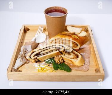 Mohn- und Apfelstrudel auf einem rustikalen Holztablett auf weißem Hintergrund. Stockfoto