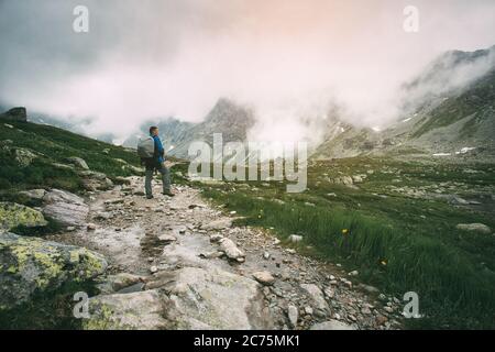 Der Mensch steht auf dem Weg in den Bergen. Hohe Gipfel der Berge im Nebel. Stockfoto