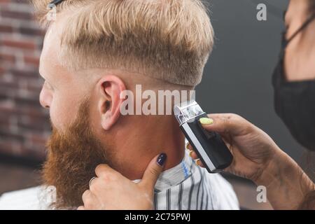 Der Mann schneidet in einem Friseurladen Haare. Haarpflege. Barber in Maske Schutz vor Viren. Haarschnitt in Quarantäne Stockfoto