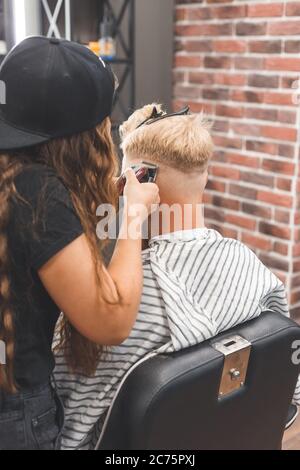 Frisur für Herren in einem Friseurladen. Haarpflege. Barber in Maske Schutz vor Viren. Haarschnitt in Quarantäne. Stockfoto