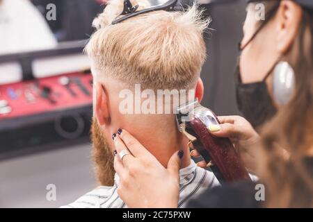 Frisur für Herren in einem Friseurladen. Haarpflege. Barber in Maske Schutz vor Viren. Haarschnitt in Quarantäne. Stockfoto