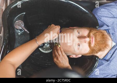 Barber Frau wäscht Kunden Mann Kopf. Konzept Barbershop. Stockfoto