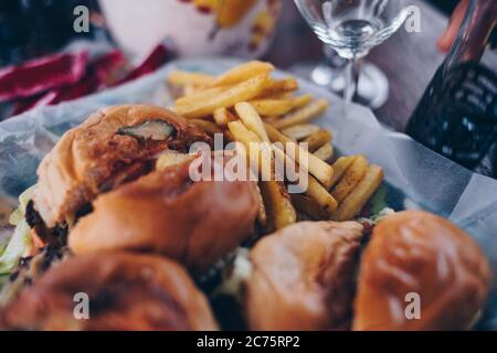 Nahaufnahme von in Scheiben geschnittenen Hamburgern und pommes auf Pergamentpapier. Selektiver Fokus. Stockfoto