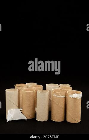 Leere Toilettenpapierrollen stapeln sich auf einem schwarzen Hintergrund Stockfoto