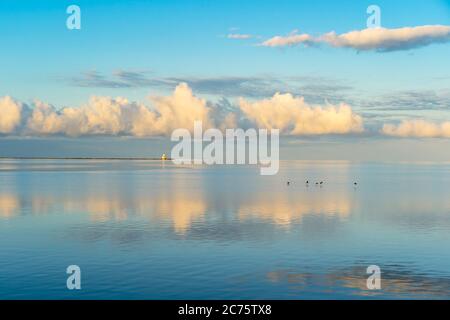 Goldene Morgenwolken spiegeln sich in den stillen Gewässern von Summerside Harbour, Prince Edward Island, Kanada. Indian Point Leuchtturm am Horizont. Stockfoto