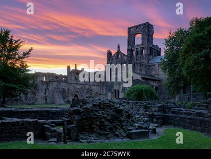 Einen traumhaften Sonnenuntergang leuchtet der Himmel hinter den Ruinen von Kirkstall Abbey, Leeds (West Yorkshire) an einem schönen Sommerabend. Stockfoto