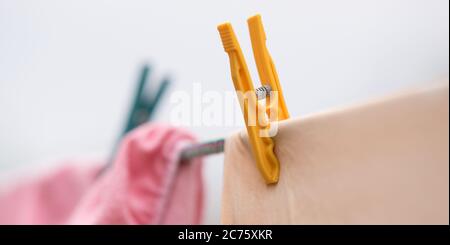 Die Kleidung wird an einem Seil mit Plastikkleider getrocknet. Nahaufnahme, schöner selektiver Fokus. Stockfoto