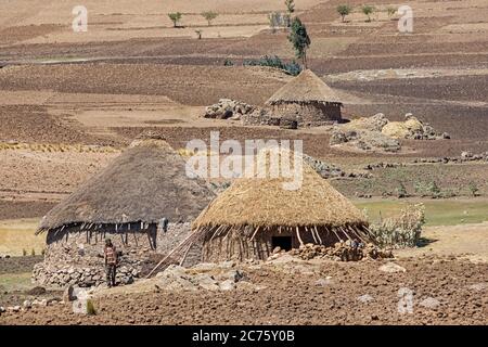 Bauer vor traditionellen runden Steinhütten mit Strohdächern im äthiopischen Hochland, Lasta Amhara Region, Äthiopien, Afrika Stockfoto