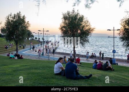 IZMIR, TÜRKEI,12. JULI 2020: Menschen, die am Ende des Sommertages Zeit am Strand von Konak und rund um die Uhr am Turm verbringen. Stockfoto