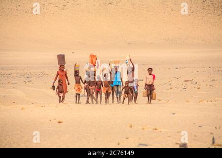 Frau Himba und Kinder arbeiten, die Wasser in ein Dorf der Himba Volk in der Kunene Region, Namibia, im Südwesten von Afrika Stockfoto