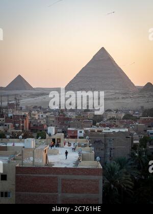 Blick auf die Pyramiden bei Sonnenuntergang vom Dach von giza und Kinder, die mit Drachen spielen Stockfoto