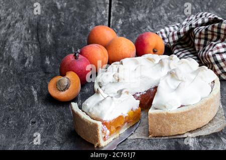 Leckere Meringuekuchen mit frischer Aprikose auf Holztisch Stockfoto