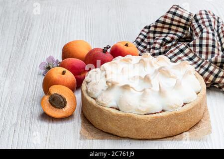 Leckere Meringuekuchen mit frischer Aprikose auf Holztisch Stockfoto