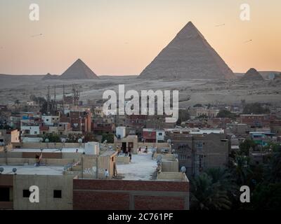 Blick auf die Pyramiden bei Sonnenuntergang vom Dach von gizeh mit spielenden Kindern Stockfoto