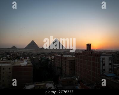 Blick auf die Pyramiden bei Sonnenuntergang vom Dach von gizeh mit Skyline Stockfoto