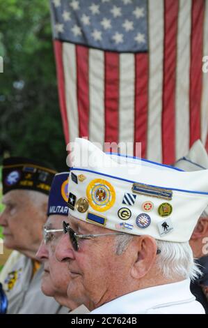 Profil Veteranen des Zweiten Weltkriegs besuchen eine Gedenkfeiertag-Zeremonie mit der amerikanischen Flagge im Hintergrund hängen Stockfoto