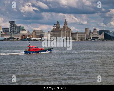 Ein Pilotboot fährt an der Vorderseite der historischen drei Grazien Gebäude an der zum UNESCO-Weltkulturerbe gehörenden Hafenpromenade von Liverpool am Fluss Mersey, Großbritannien vorbei Stockfoto