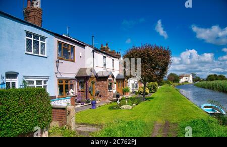 Die farbenfrohe Terrasse der New Lane Cottages neben dem Leeds to Liverpool Canal in Burscough, Lancashire Stockfoto