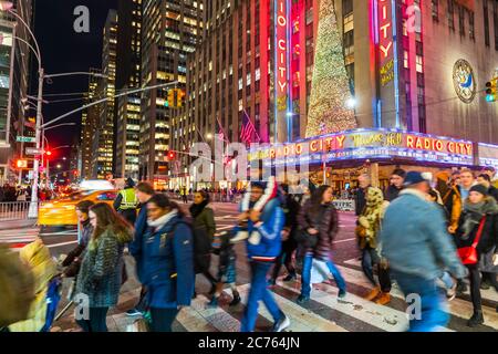 Eine Menschenmenge überquert die 6th Avenue vor der Radio City Music Hall Stockfoto