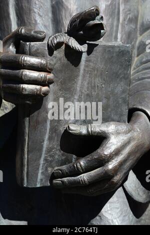 Detail einer Bronzestatue in Santa Fe, New Mexico, von einem hispanischen katholischen Priester, der eine Bibel in der Hand hält. Stockfoto