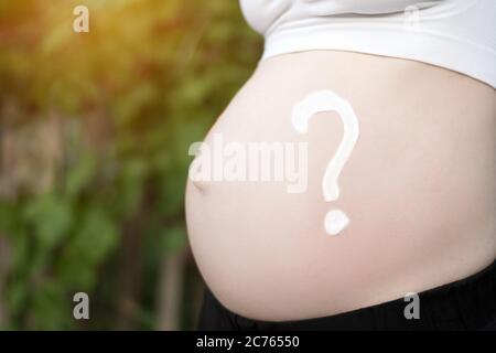 Fragezeichen auf einem schwangeren weiblichen Bauch gezeichnet. Schwangeres Konzept. Nahaufnahme Stockfoto