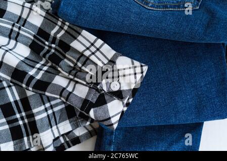 Kleidungskonzept. Kariertes Hemd und Jeans auf Holzhintergrund. Details Stockfoto