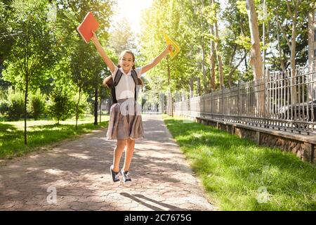 Zurück zur Schule. In voller Länge Porträt von aufgeregt kleinen Schulmädchen springen auf Stadt Straße. Stockfoto