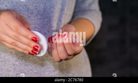 Frau entfernt den Nagellack. Frau Hand entfernen roten Nagellack mit weißem Wattepad. Stockfoto