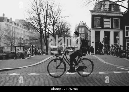 Amsterdam - ein Radfahrer kommt vorbei. Auf der Lijnbaansgracht an der Kreuzung mit Spiegelgracht stehend, mit De Saloon voraus. NL, Niederlande. Stockfoto