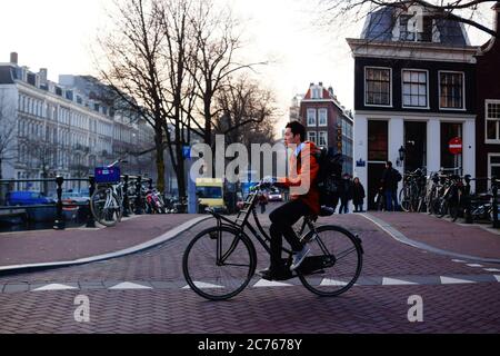 Amsterdam - ein Radfahrer kommt vorbei. Auf der Lijnbaansgracht an der Kreuzung mit Spiegelgracht stehend, mit De Saloon voraus. NL, Niederlande. Stockfoto