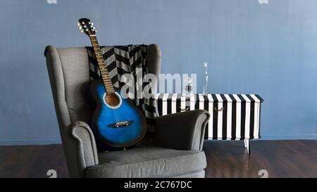 Home Interieur einer der Ecken des Raumes. Nahaufnahme eines bequemen Sessels mit Kart und Gitarre im Zimmer. Stockfoto