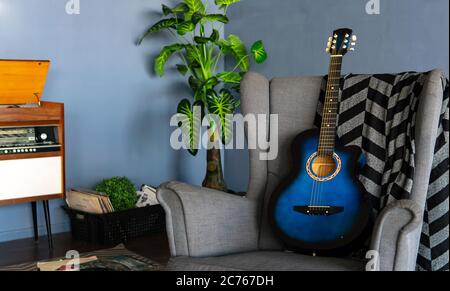 Home Interieur einer der Ecken des Raumes. Nahaufnahme eines bequemen Sessels mit Kart und Gitarre im Zimmer. Stockfoto