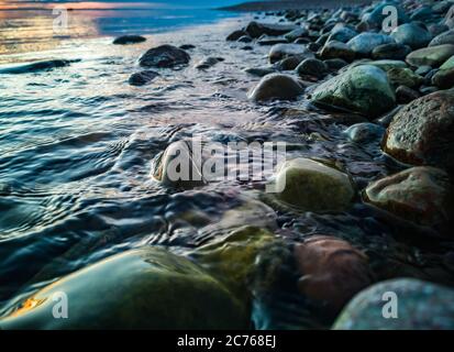 Das Meer in der Ostsee an einem ruhigen Abend, wenn das Wasser über runde Steine am Strand spült Stockfoto
