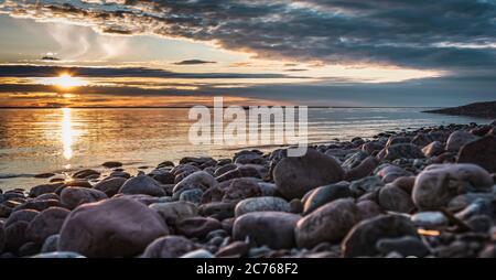 Sonnenuntergang an der Ostsee mit wunderschönen Natursteinen an der schwedischen Ostseeküste, wo das Meer am Abend ruhig ist Stockfoto