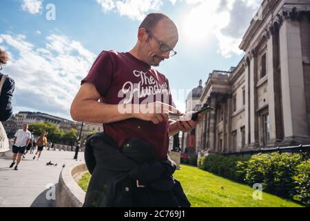 London / UK - 07/11/2020: Älterer Mann benutzt sein Telefon auf den Straßen von Soho nach Coronavirus-Sperre Stockfoto