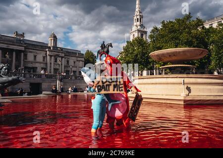 London / UK - 07/11/2020: Paar in Kostümen und mit Spruchbändern im Brunnen stehen, nachdem die Tierrechtsgruppe Brunnen rot einfärbt Stockfoto