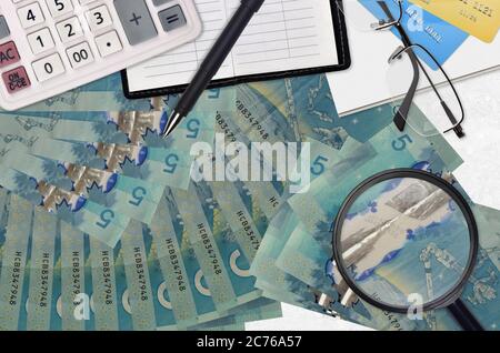 5 kanadische Dollar Rechnungen und Rechner mit Brille und Stift. Tax Payment Saison Konzept oder Investment-Lösungen. Suche nach einem Job mit hohem Gehalt Ohr Stockfoto