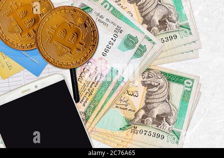 10 Sri Lanka Rupien Scheine und goldene Bitcoins mit Smartphone und Kreditkarten. Investitionskonzept für Kryptowährungen. Krypto-Bergbau oder Handel mit Transakteen Stockfoto